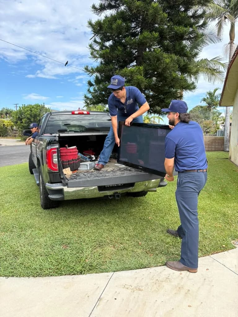 Mundo Junk Removal & Recycling crew loading a flat-screen TV into the truck for recycling