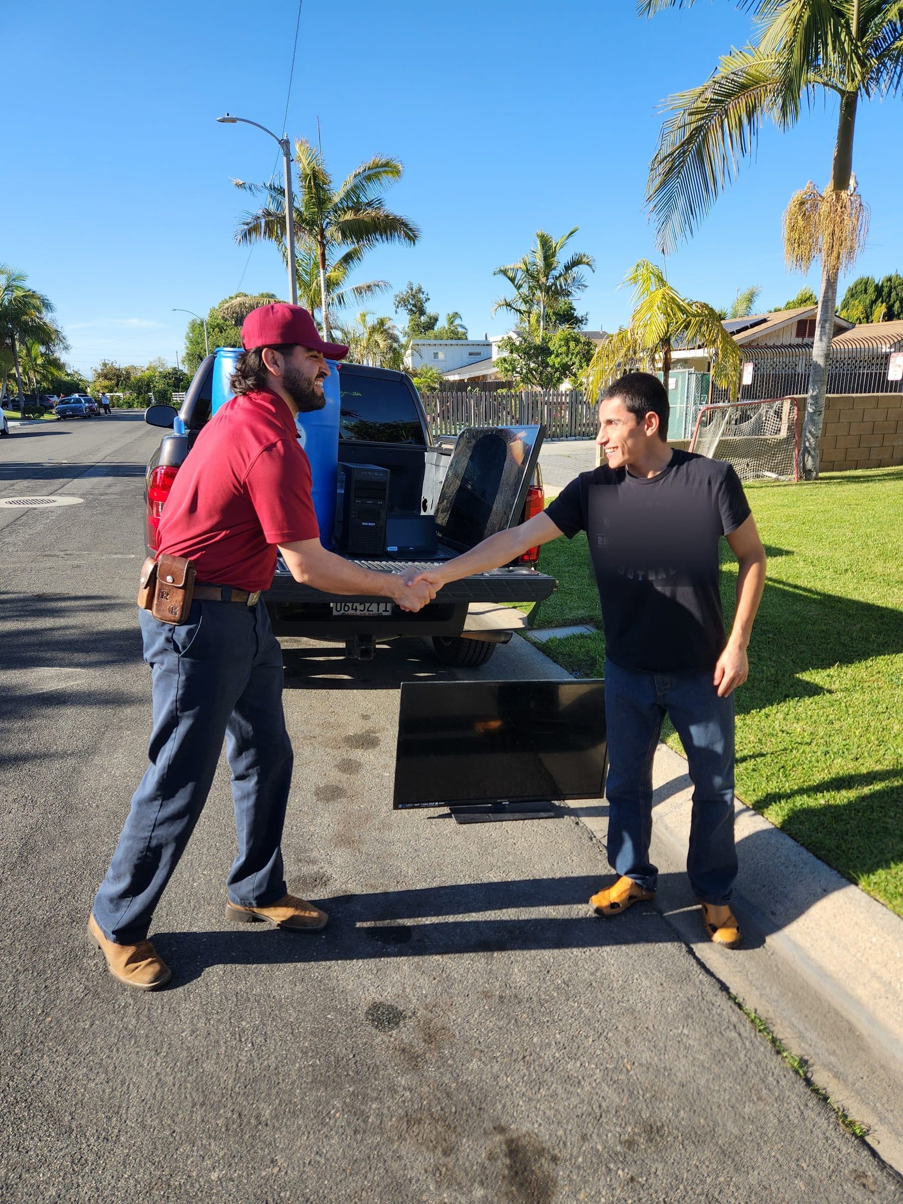 Crew picking up a TV and a computer tower from a driveway
