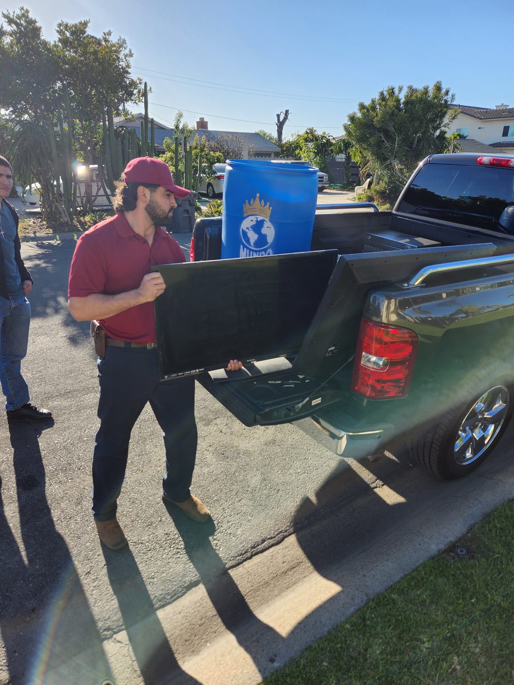 Crew member loading a TV into the truck for recycling